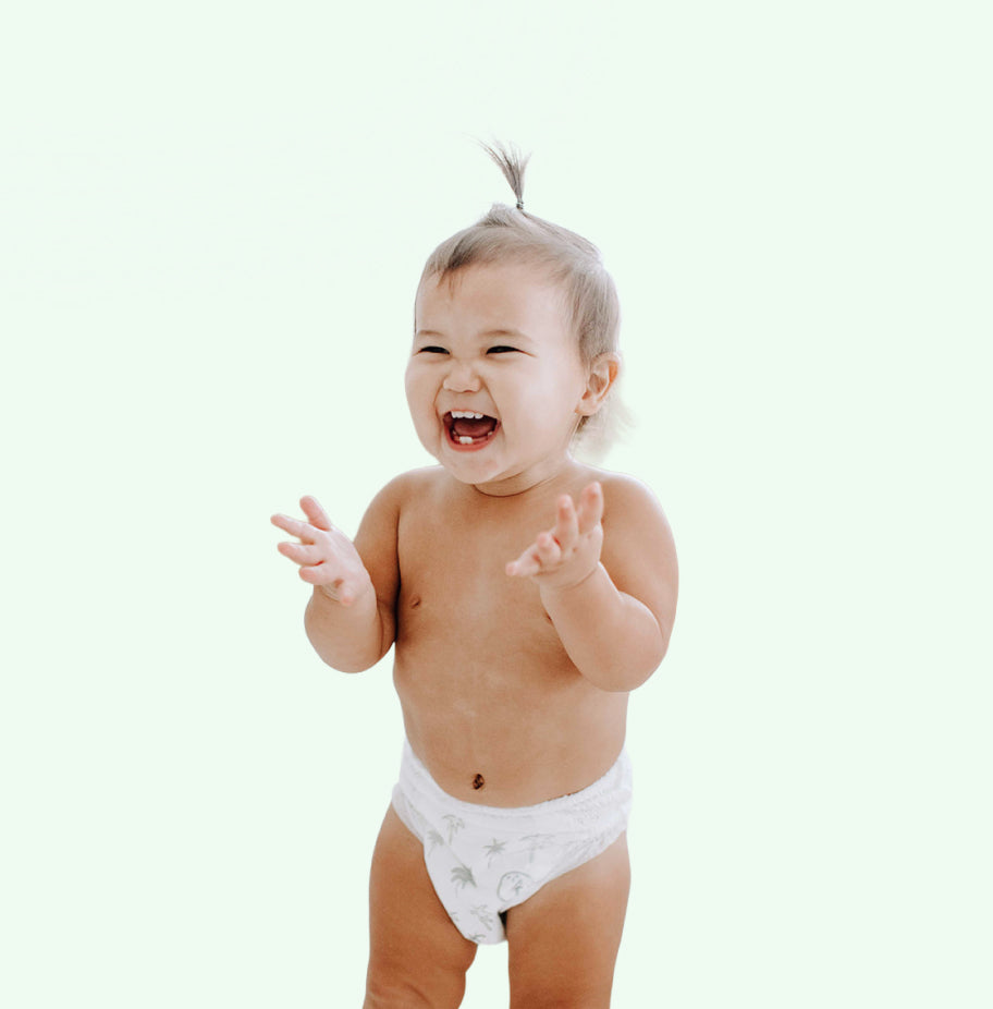 Baby in a white diaper clapping hands on a light background