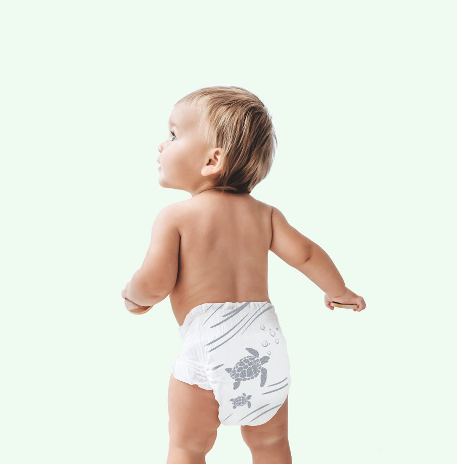 Child wearing a white diaper with a turtle design on a plain background