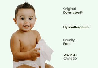 Baby holding a wipe with Dermatest branding on a white background

