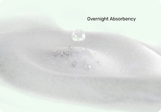 Close-up of a white diaper with water droplets and text 'Overnight Absorbency'.
