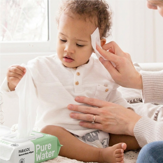 Child being comforted by a hand with a wipe, next to a box of Parasol Pure Water wipes.
